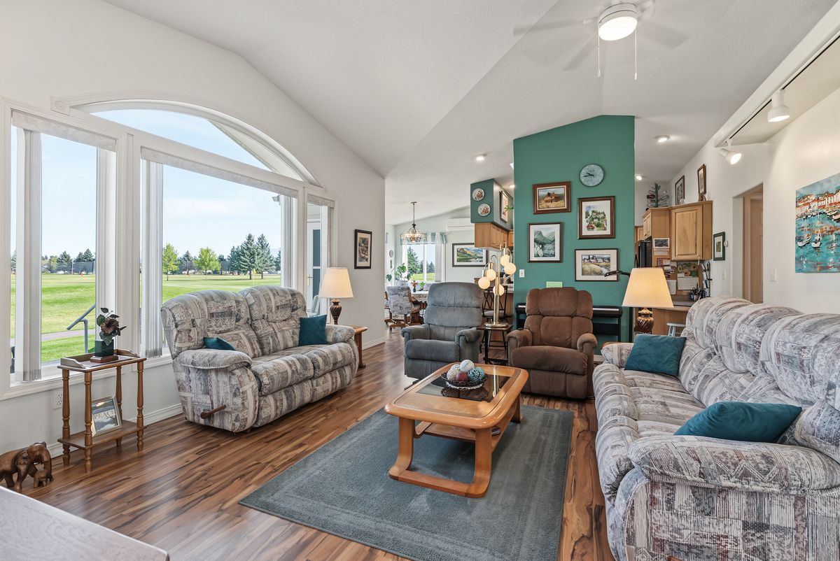 Living room with a vaulted ceiling and an arched window looking out to the golf course