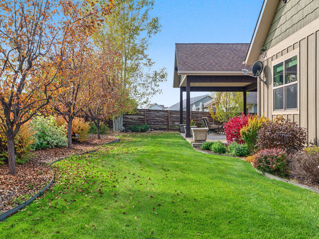 Landscaped, fenced backyard with mature trees in fall color