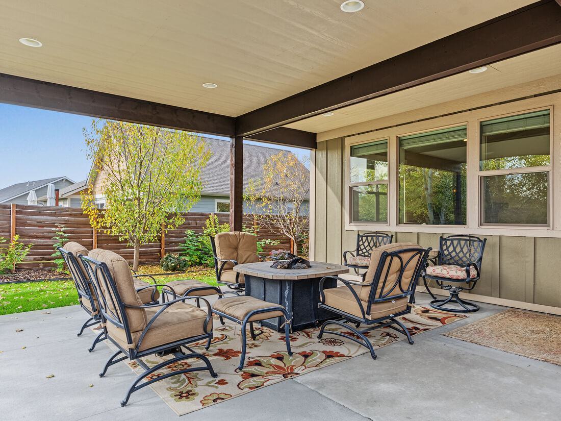 Oversized covered back patio with dining and fire pit seating overlooking the landscaped yard