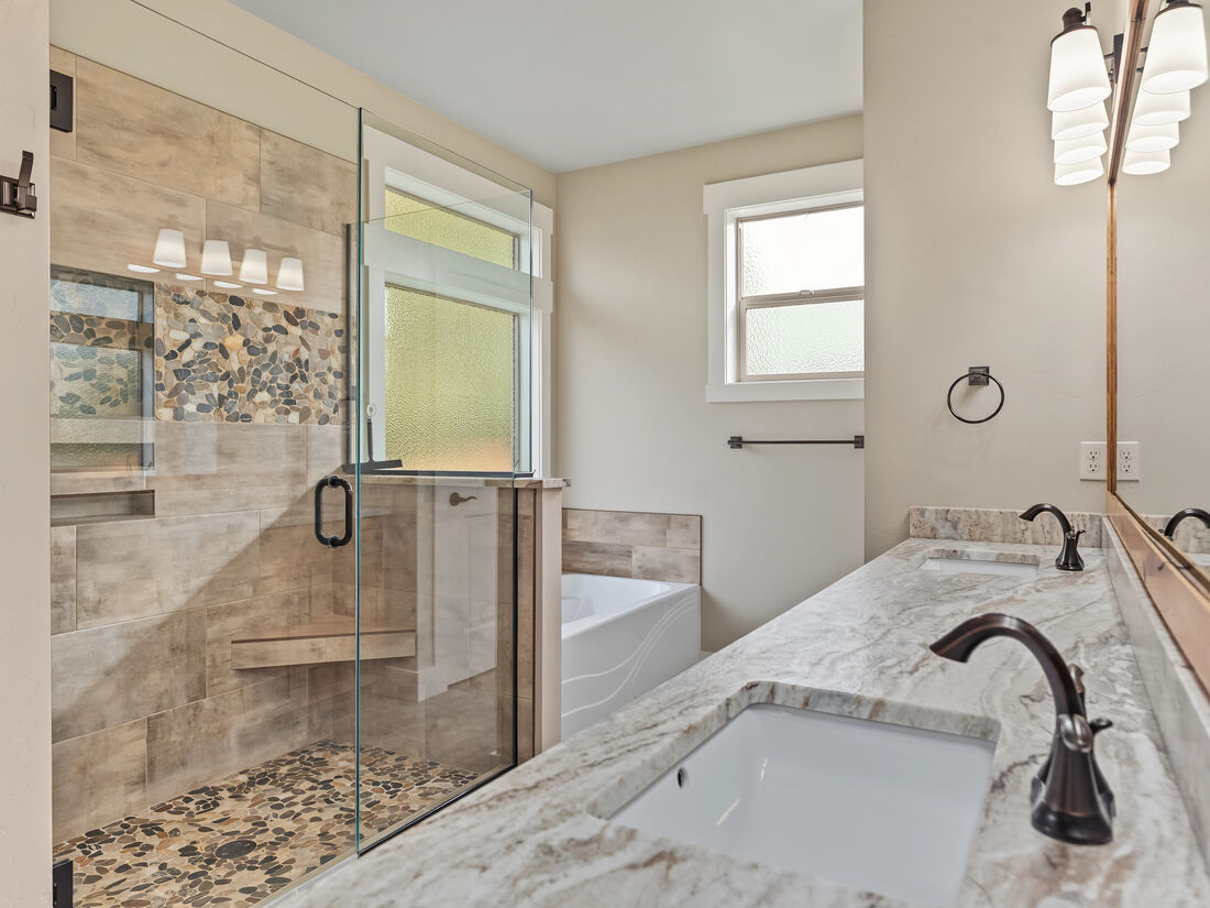 Primary bathroom with tiled walk-in shower, soaking tub, and double vanity