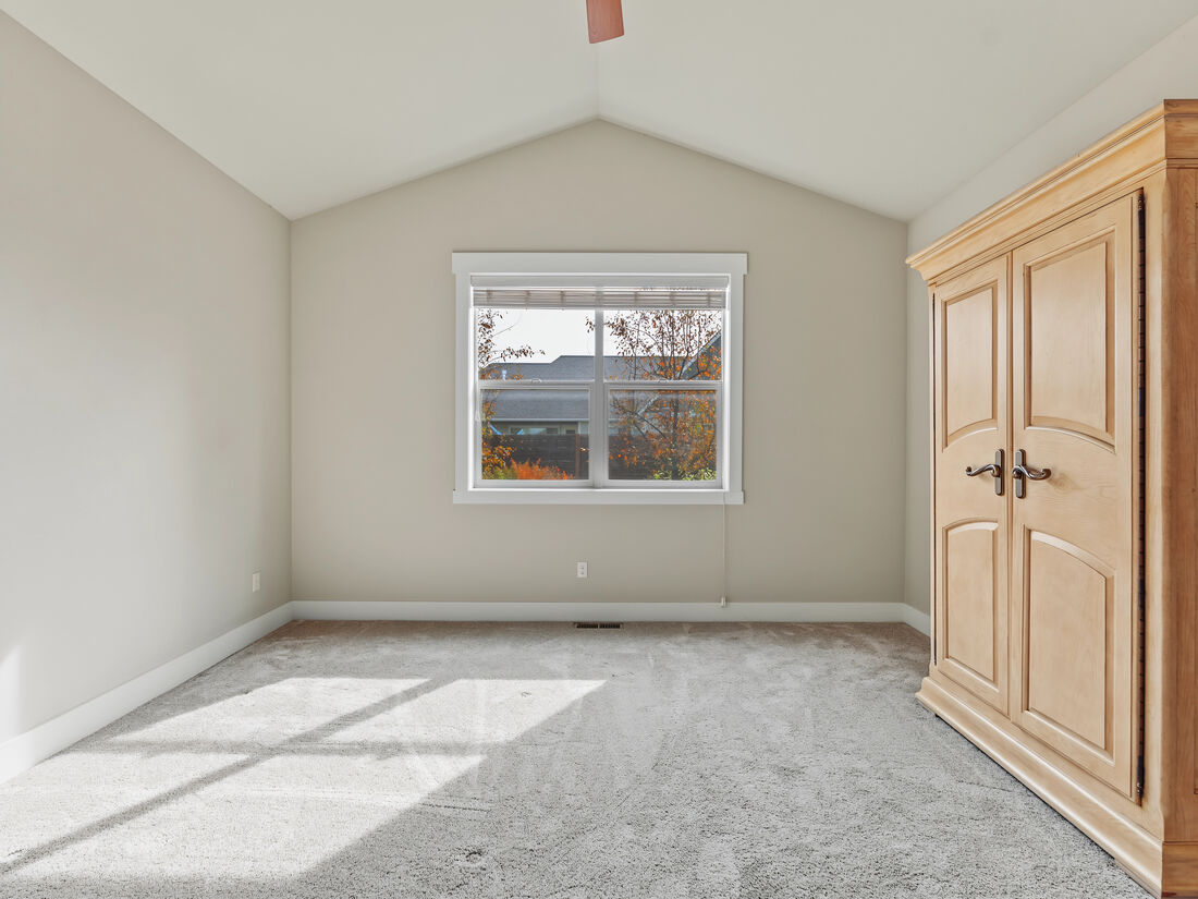 Primary bedroom with vaulted ceiling and ceiling fan