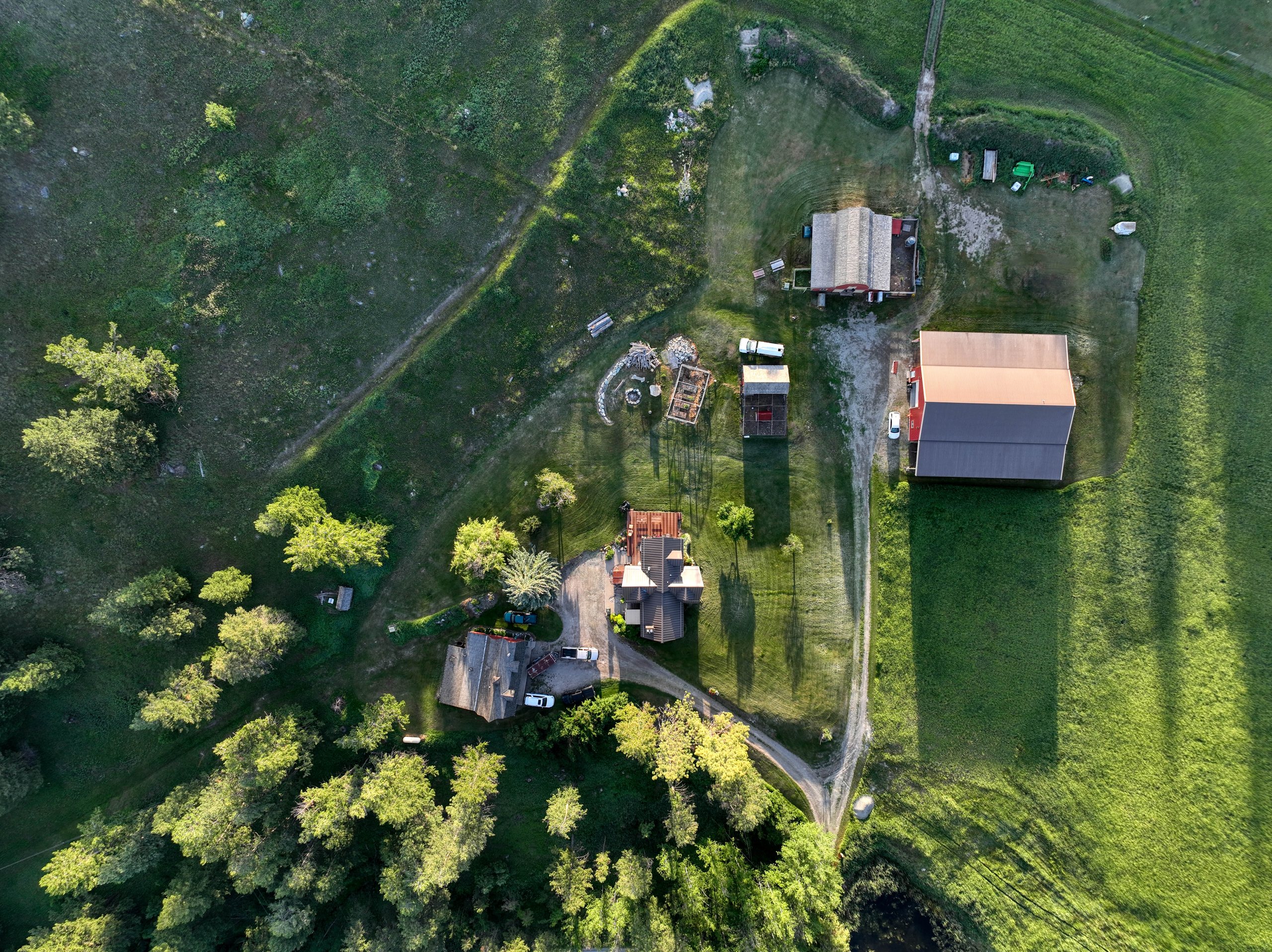 Overhead drone view of the homestead buildings and garden surrounded by trees