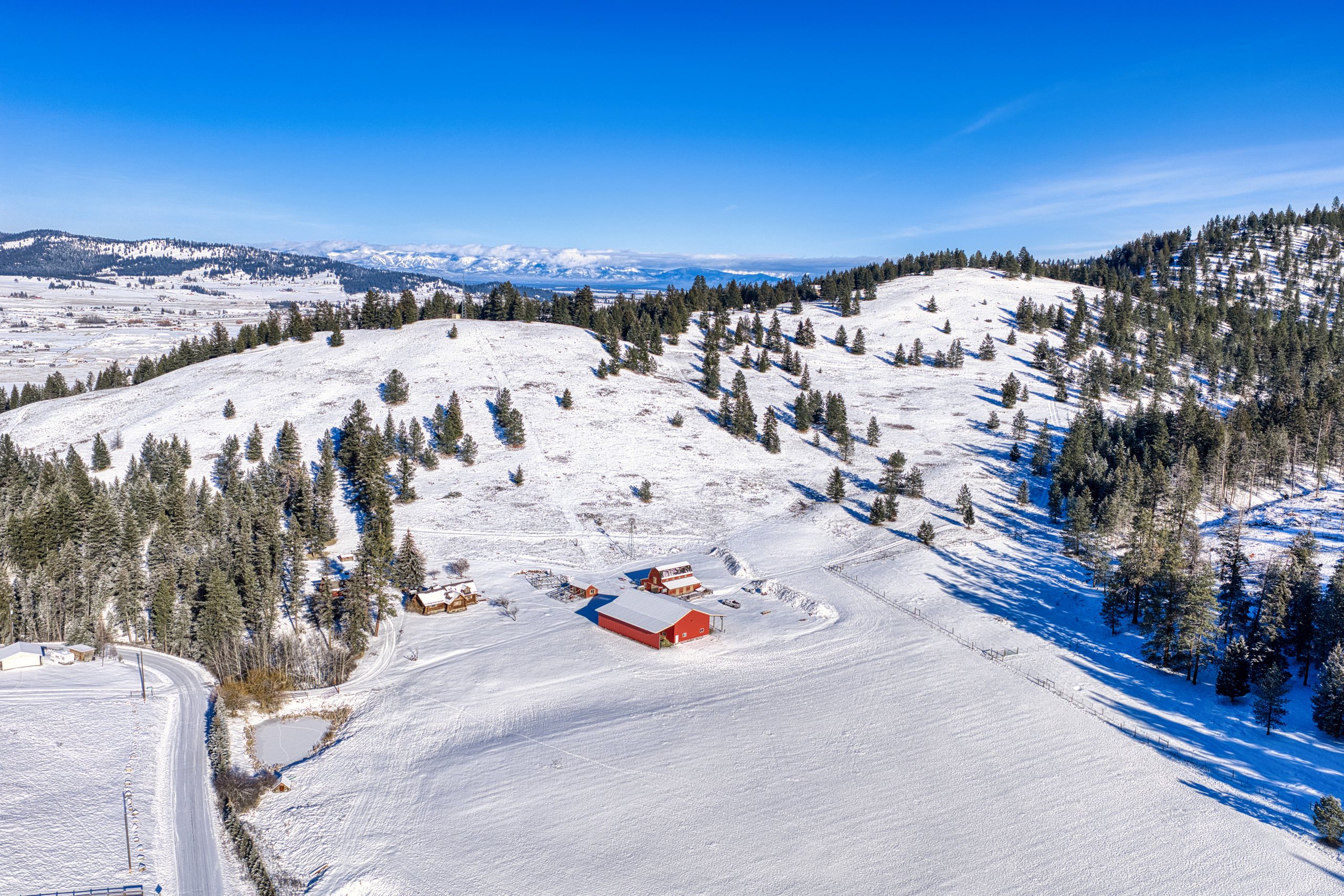 Winter aerial of the property showing the plowed access road, pond, and snow-covered fields