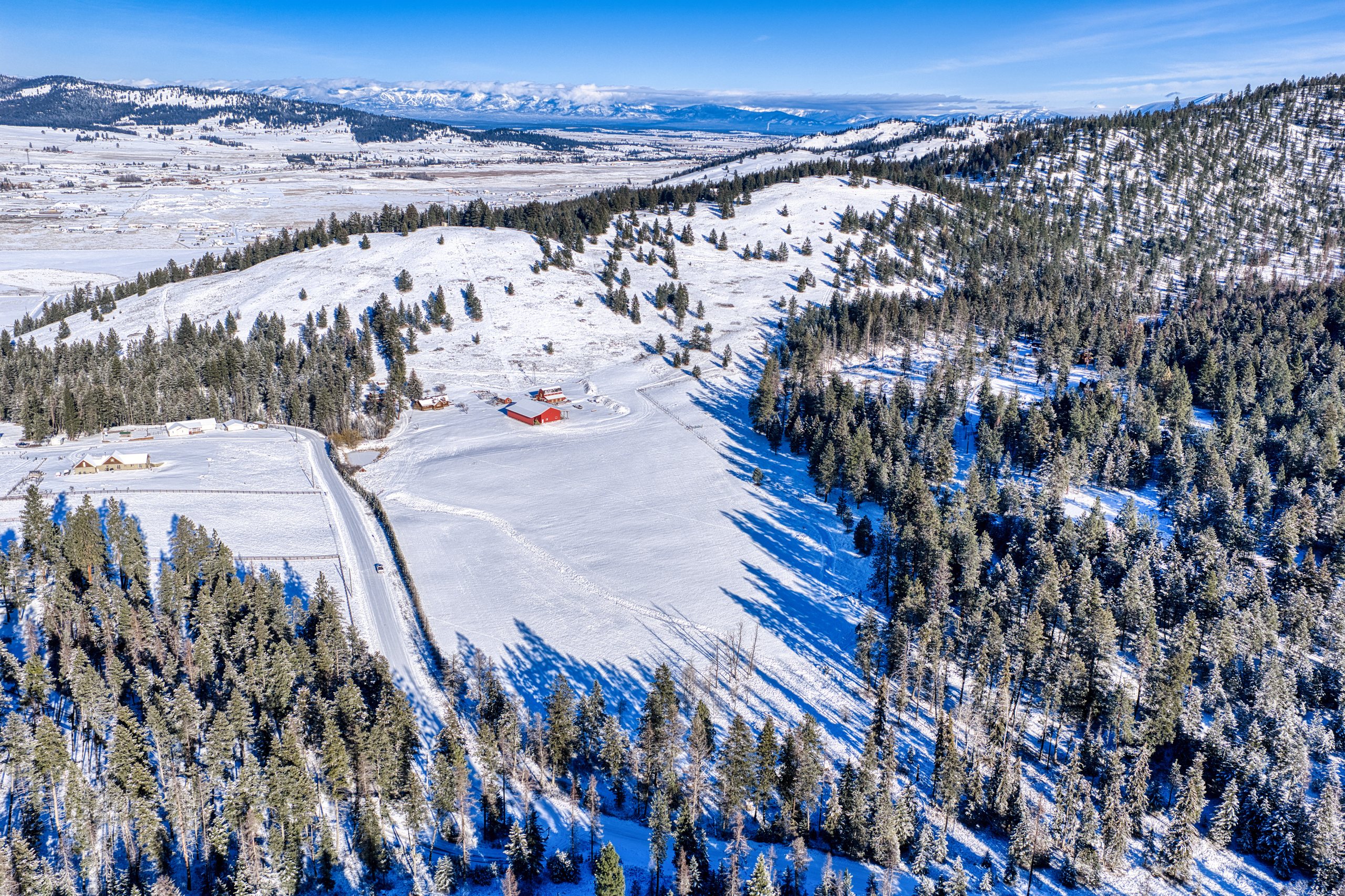 Winter aerial looking across the land toward the Flathead Valley and snow-capped peaks