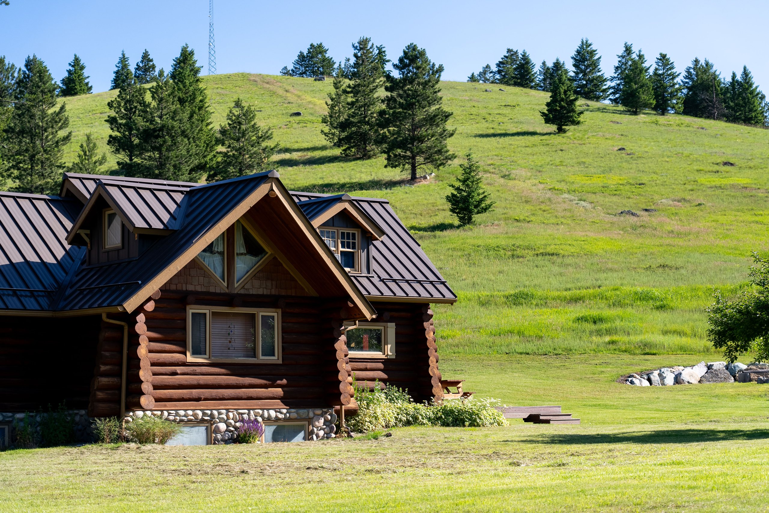 Log home exterior set against open meadow and forested hills