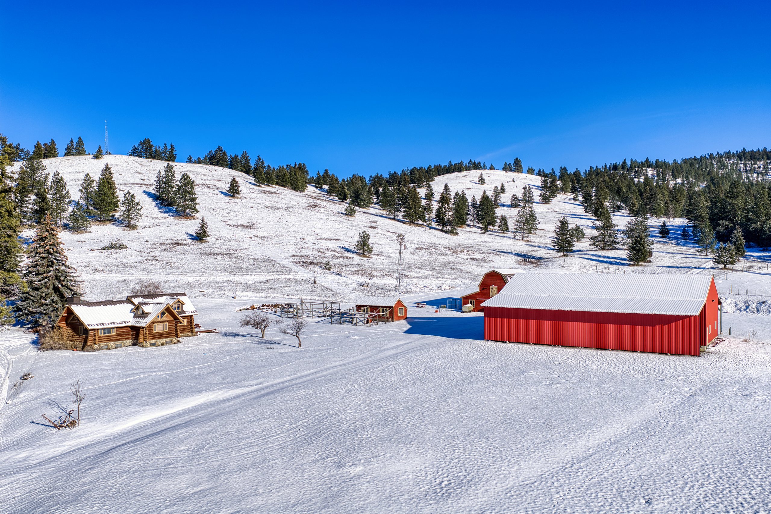 The shop and log home in winter, with snow across the property